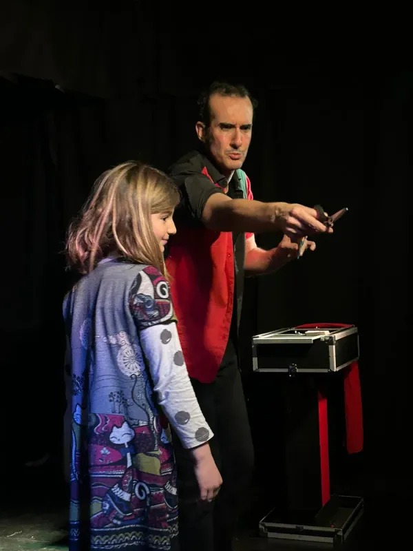 Niña participando en un truco de magia sobre el escenario